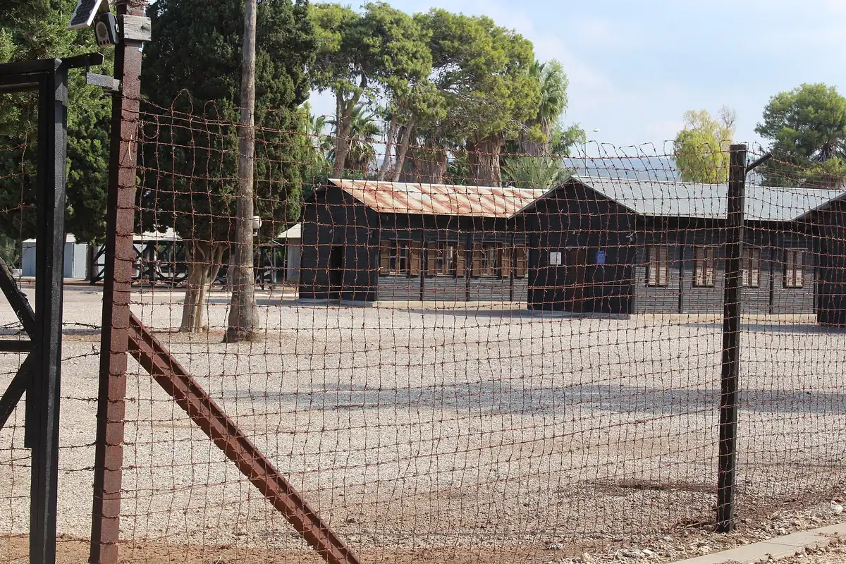 Wooden barracks behind a barbed-wire fence at the Atlit detention camp heritage site