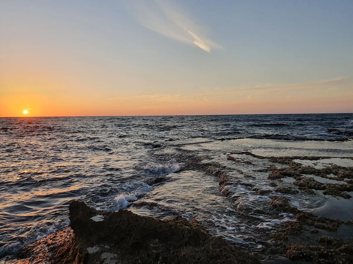 Sunset over the sea from the rocky shore of the Dor-HaBonim beach reserve