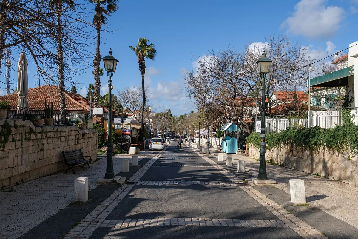 The restored main street of the old moshava, lined with low houses, street lamps and palm trees