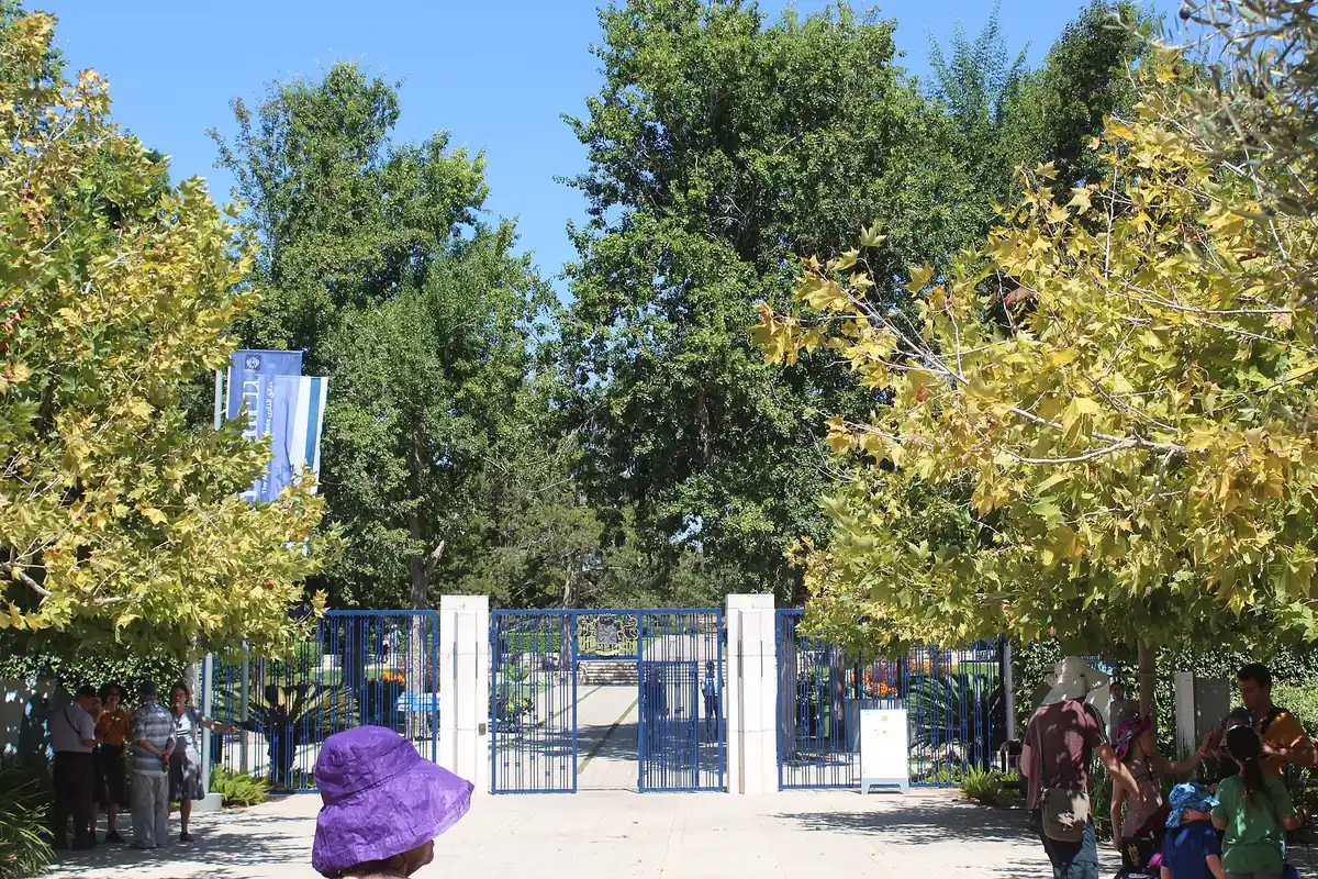 Visitors at the entrance gate of the Ramat HaNadiv gardens, among tall trees